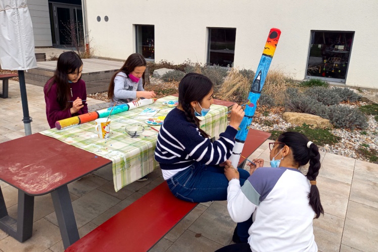 Hortkinder bemalen Pfosten für die Abgrenzung der Blühwiese zur Pausenwiese der Schule